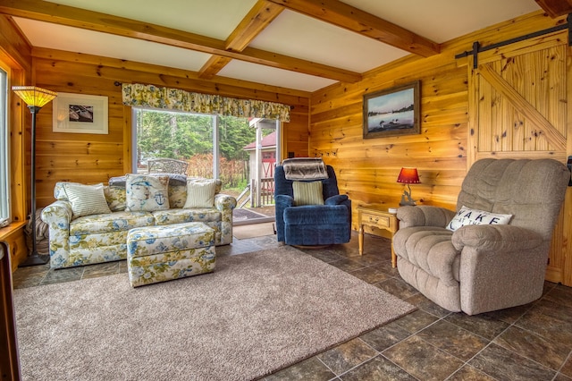 living room with beamed ceiling, a barn door, and dark tile patterned floors