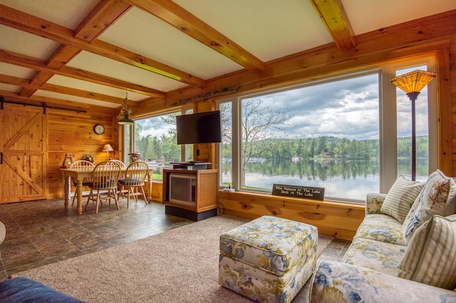 living room with a barn door, beamed ceiling, and wooden walls