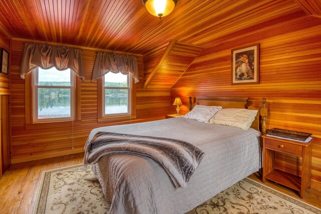 bedroom featuring lofted ceiling, wood walls, wooden ceiling, and hardwood / wood-style flooring