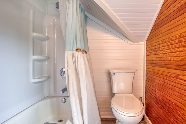 bathroom with toilet, wooden walls, lofted ceiling, and shower / bathtub combination with curtain