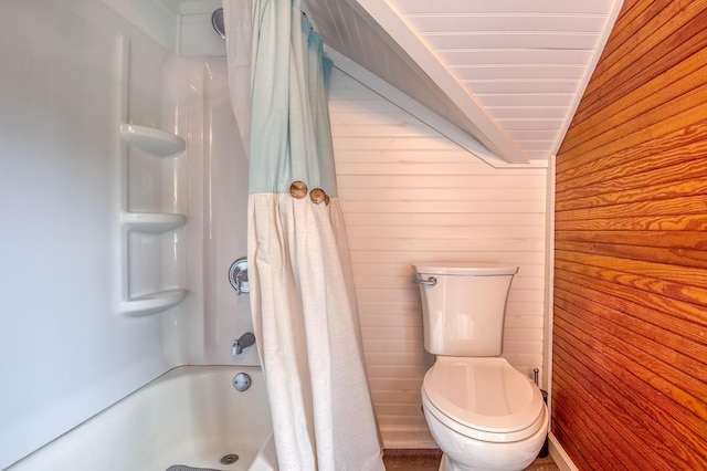 full bathroom featuring vaulted ceiling, wood walls, toilet, and shower / bath combo with shower curtain