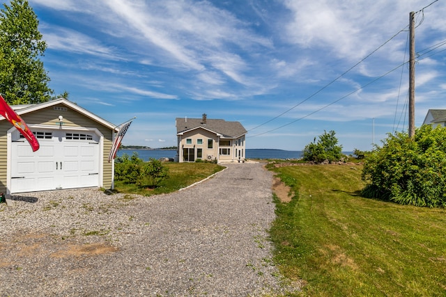 exterior space featuring a garage, a water view, and a front yard