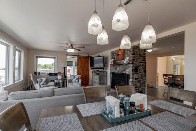 dining room with a barn door, ceiling fan, dark hardwood / wood-style floors, a baseboard radiator, and a fireplace