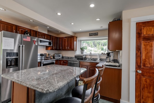 kitchen featuring sink, stone countertops, a breakfast bar area, and stainless steel appliances