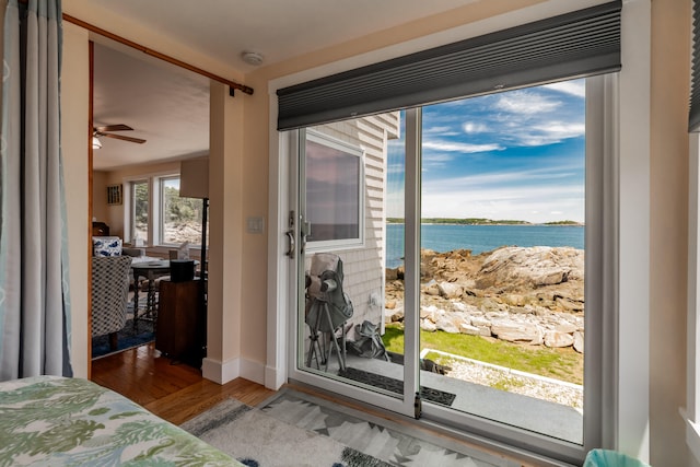 bedroom featuring a water view, hardwood / wood-style flooring, and access to outside