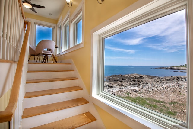 stairs featuring a water view and ceiling fan