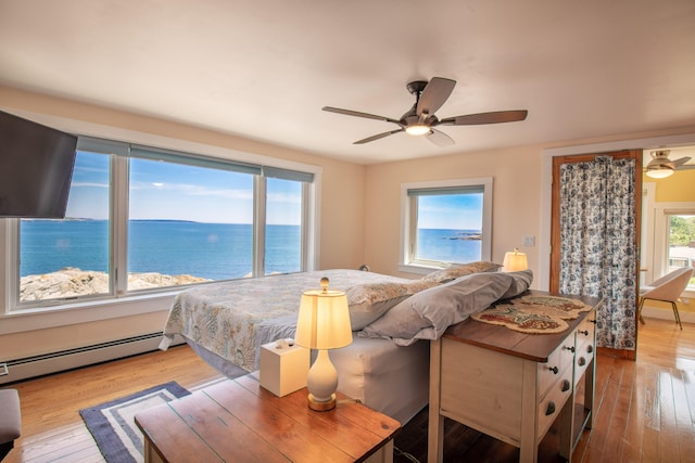 bedroom with a baseboard radiator, a water view, ceiling fan, and light wood-type flooring