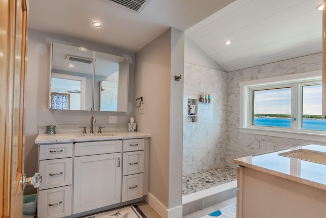 bathroom with vanity, a tile shower, lofted ceiling, and tile patterned floors