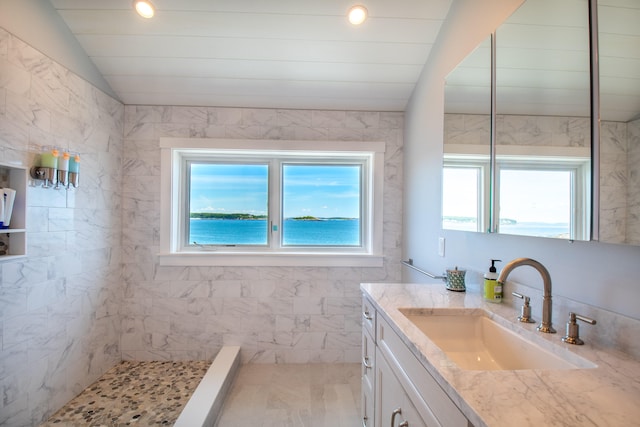 bathroom with lofted ceiling, a water view, vanity, tile patterned floors, and a tile shower