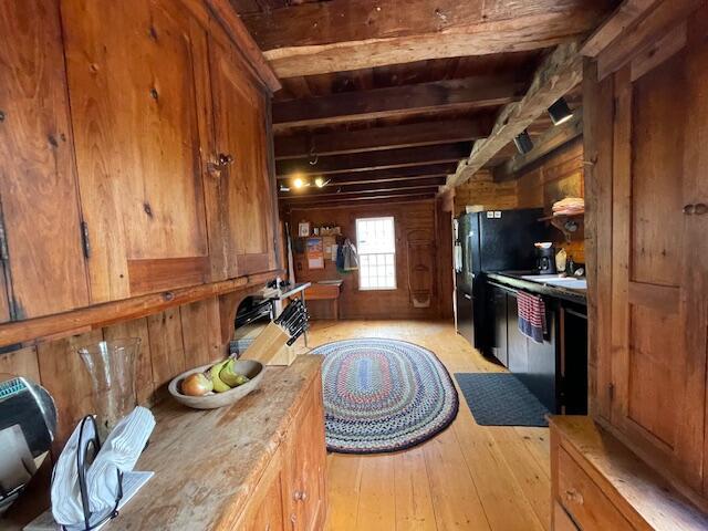 38 Kingsbury Ln, Perry, ME 04667 - kitchen with light wood-style flooring, brown cabinets, wooden walls, beam ceiling, and light countertops
