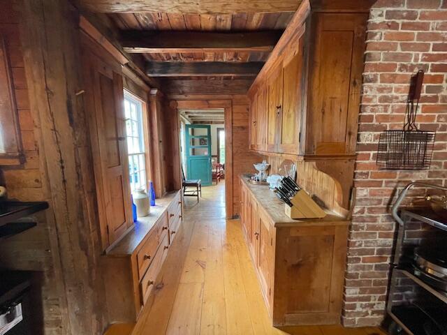 38 Kingsbury Ln, Perry, ME 04667 - kitchen featuring a wood ceiling with exposed beams, light wood finished floors, wood walls, light countertops, and brown cabinets