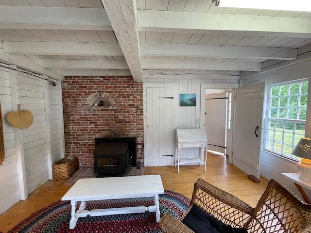 38 Kingsbury Ln, Perry, ME 04667 - living area with light wood-style flooring, wood walls, a wood stove, and a wood ceiling with exposed beams