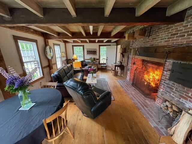 38 Kingsbury Ln, Perry, ME 04667 - living area featuring a brick fireplace, wood-type flooring, beamed ceiling, and brick wall