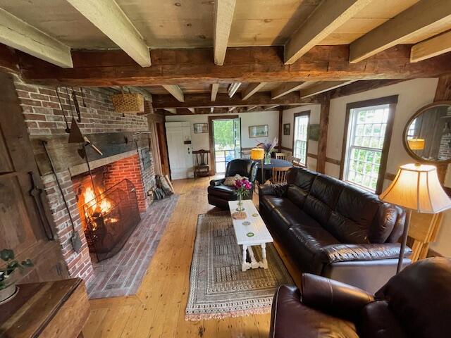 38 Kingsbury Ln, Perry, ME 04667 - living room featuring hardwood / wood-style flooring, beam ceiling, healthy amount of natural light, and a brick fireplace