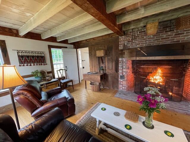 38 Kingsbury Ln, Perry, ME 04667 - living room featuring wood-type flooring, a brick fireplace, and a wooden ceiling with exposed beams