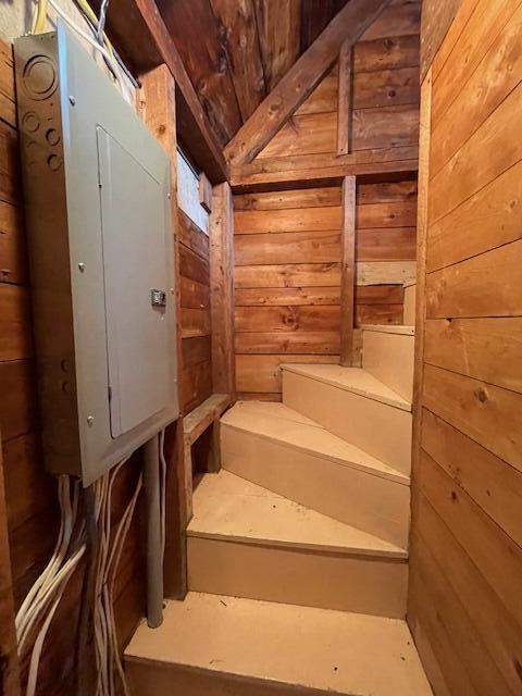38 Kingsbury Ln, Perry, ME 04667 - staircase featuring wood walls, lofted ceiling, wood ceiling, and electric panel