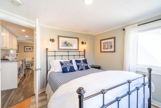 bedroom featuring independent washer and dryer, hardwood / wood-style floors, and ornamental molding