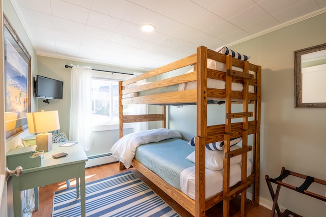 bedroom with crown molding, light hardwood / wood-style flooring, and a baseboard heating unit