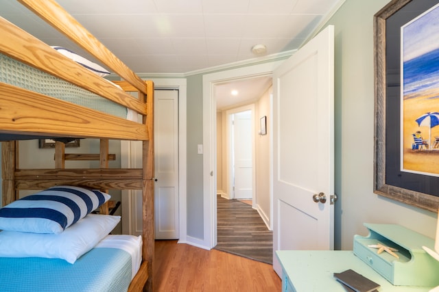 bedroom featuring crown molding, light hardwood / wood-style flooring, and a closet