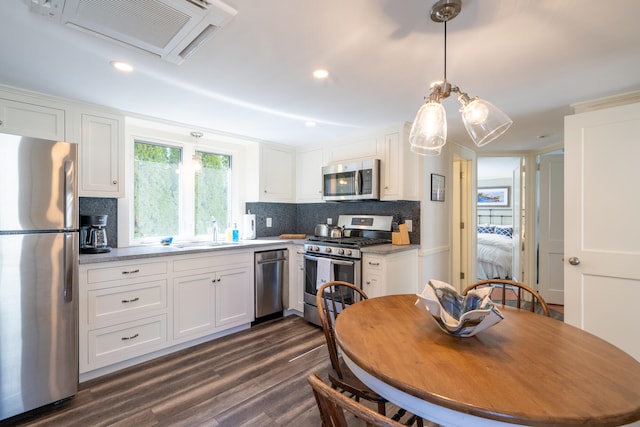 kitchen featuring dark wood-type flooring, tasteful backsplash, stainless steel appliances, and white cabinetry