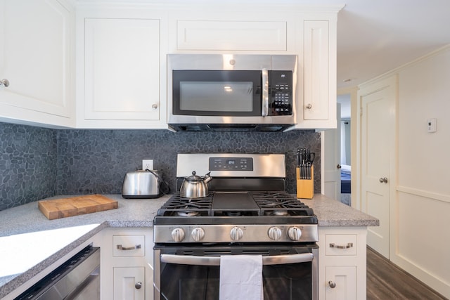 kitchen with dark wood-type flooring, appliances with stainless steel finishes, tasteful backsplash, and white cabinets