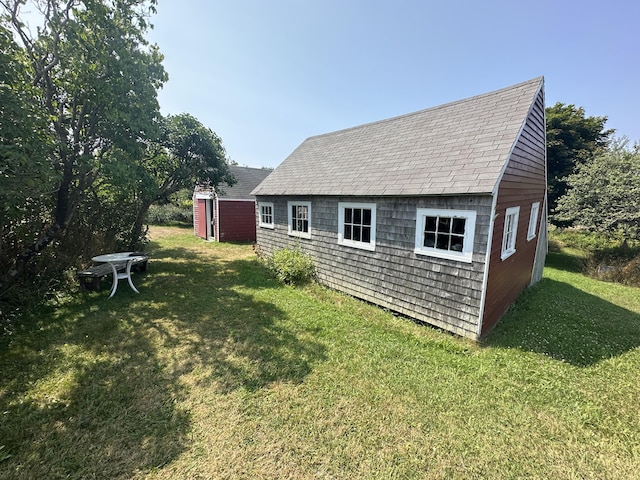 rear view of house featuring an outbuilding and a lawn