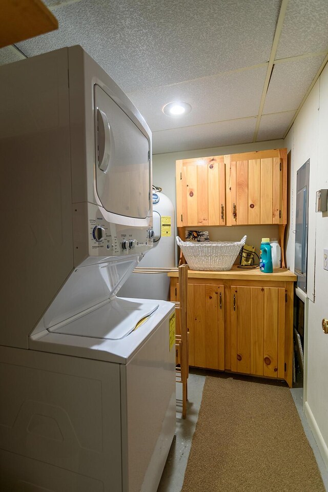 washroom with stacked washer and clothes dryer and cabinets