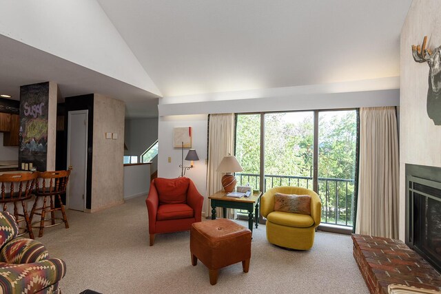 carpeted living room with a healthy amount of sunlight, a brick fireplace, and vaulted ceiling