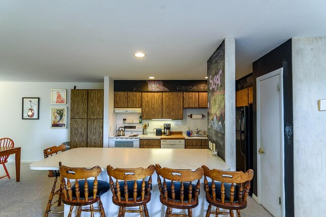 kitchen featuring a breakfast bar, sink, carpet flooring, and white appliances