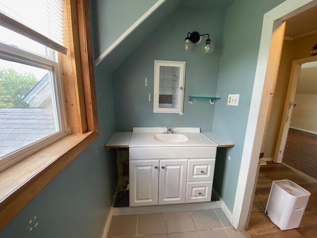 bathroom featuring hardwood / wood-style flooring, vaulted ceiling, and vanity