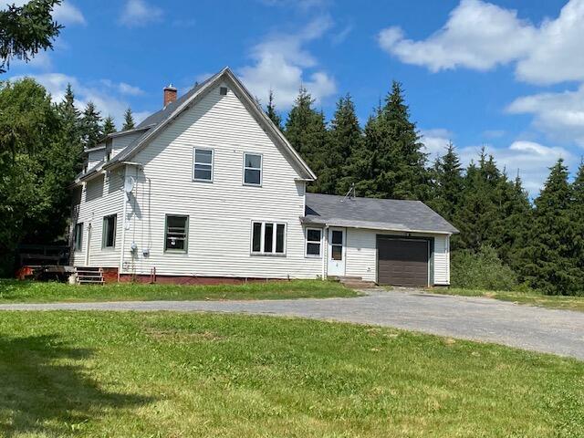 view of side of home featuring a garage and a lawn