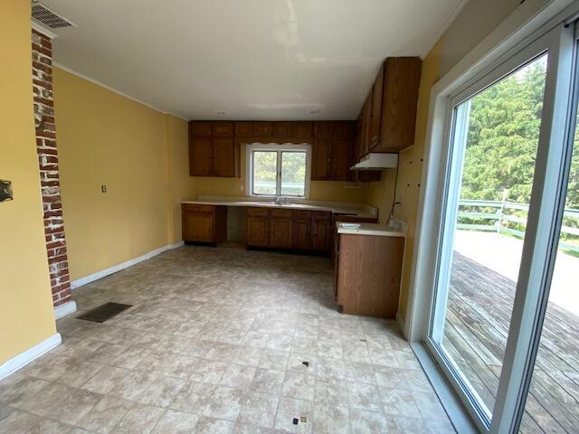 kitchen featuring light tile patterned flooring, sink, and brick wall