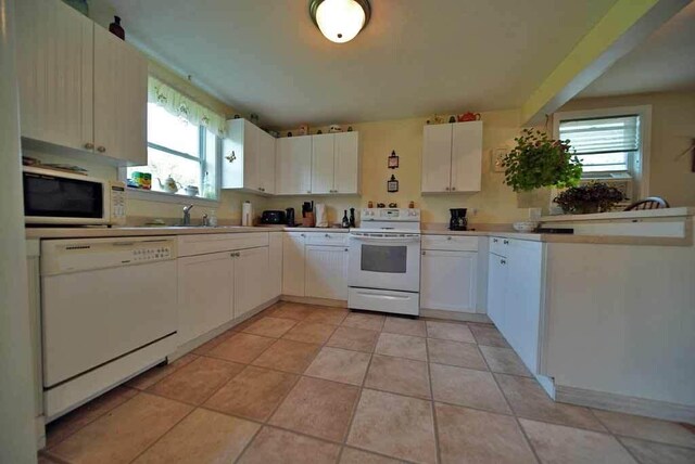 kitchen featuring sink, white cabinetry, light tile patterned floors, and white appliances