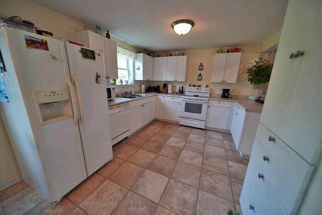 kitchen with light tile patterned flooring, white cabinetry, white appliances, and sink