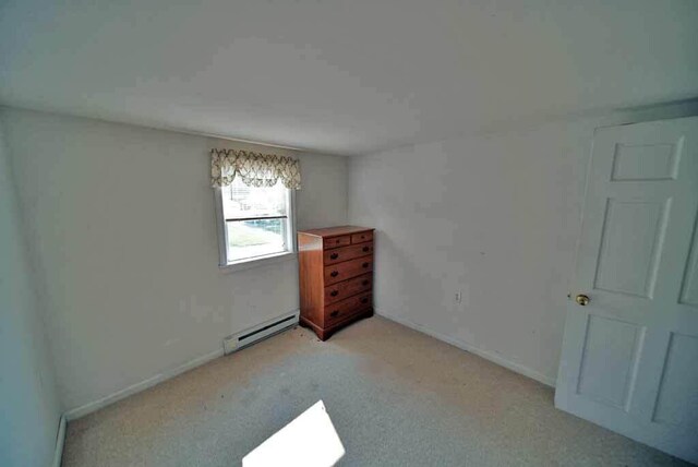 interior space featuring a baseboard heating unit and light colored carpet