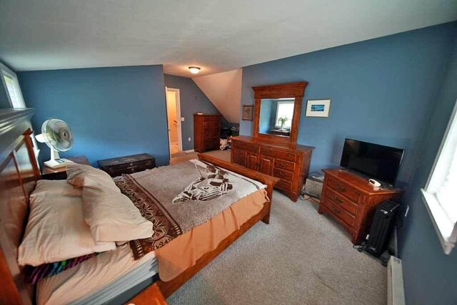 carpeted bedroom with lofted ceiling, multiple windows, and a baseboard radiator