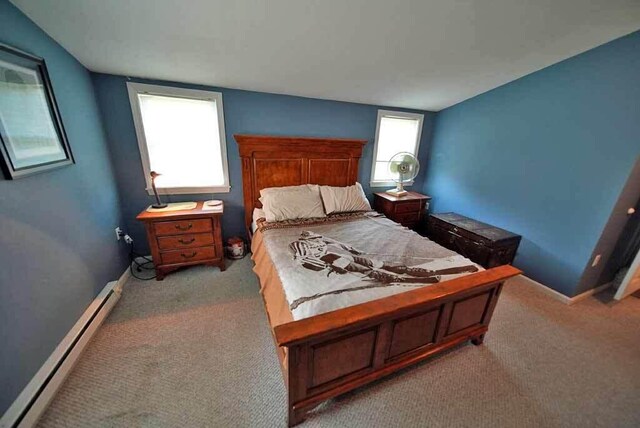 bedroom with light carpet and a baseboard heating unit