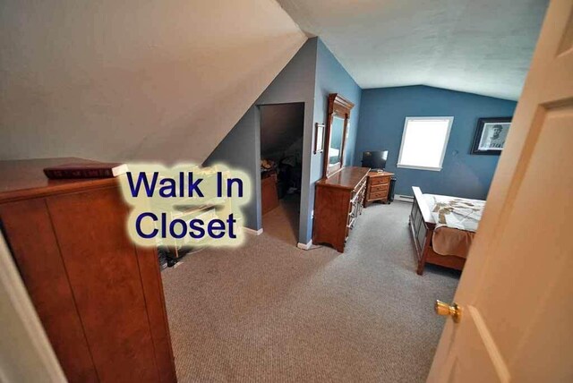 carpeted bedroom featuring baseboard heating and vaulted ceiling