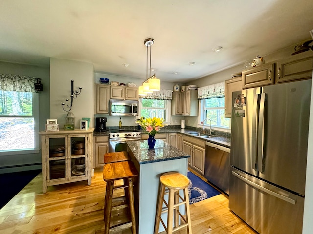 kitchen with a breakfast bar, light hardwood / wood-style flooring, a center island, appliances with stainless steel finishes, and sink