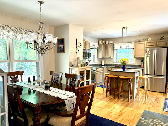 dining room with light hardwood / wood-style floors, a notable chandelier, sink, and plenty of natural light