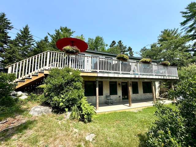 rear view of property with a deck, a yard, and a patio area