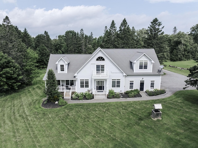 new england style home featuring covered porch and a front lawn