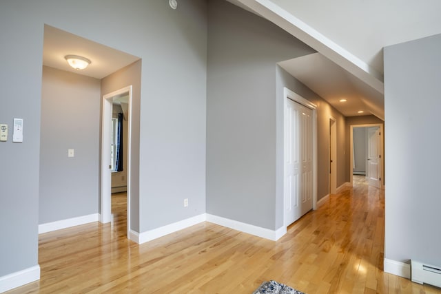 corridor with baseboard heating and light hardwood / wood-style flooring