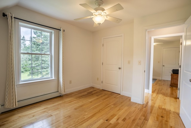 unfurnished bedroom featuring baseboard heating, ceiling fan, and light wood-type flooring