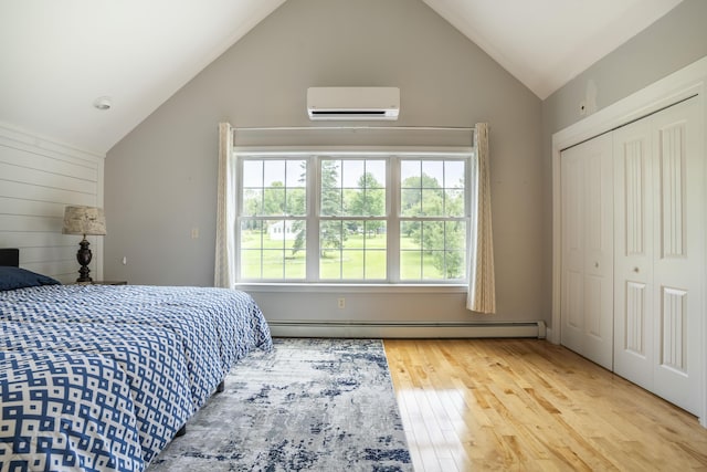 bedroom featuring a baseboard radiator, a closet, a wall mounted air conditioner, lofted ceiling, and hardwood / wood-style floors