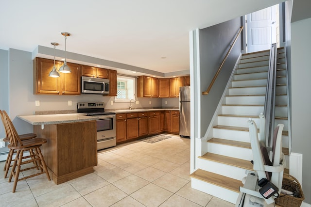 kitchen featuring kitchen peninsula, hanging light fixtures, stainless steel appliances, sink, and a kitchen bar