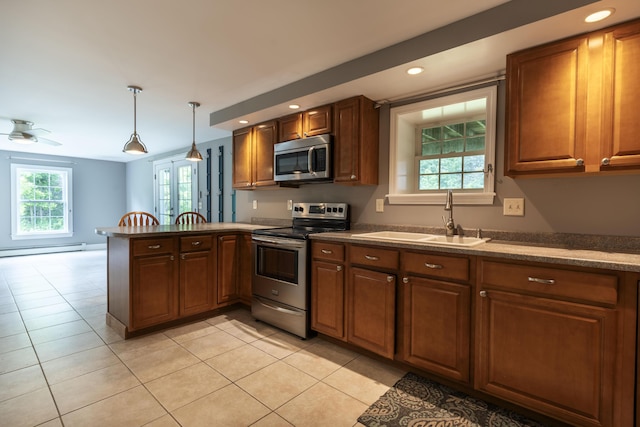 kitchen featuring kitchen peninsula, stainless steel appliances, sink, a baseboard radiator, and pendant lighting