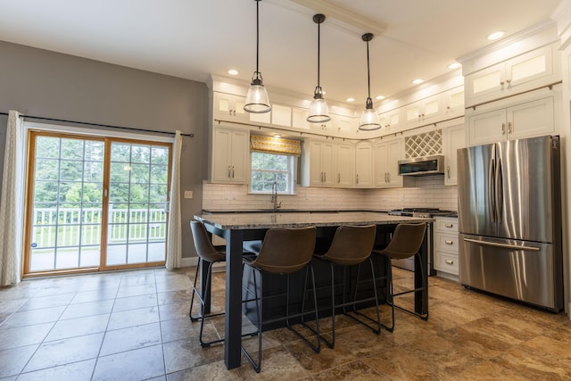 kitchen with appliances with stainless steel finishes, decorative light fixtures, a breakfast bar, backsplash, and sink