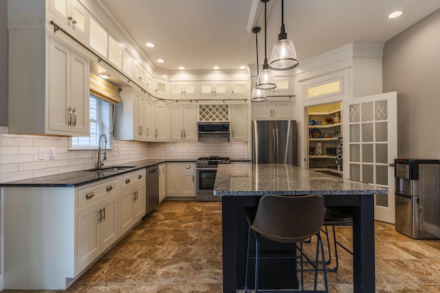 kitchen with sink, stainless steel appliances, decorative backsplash, and a center island