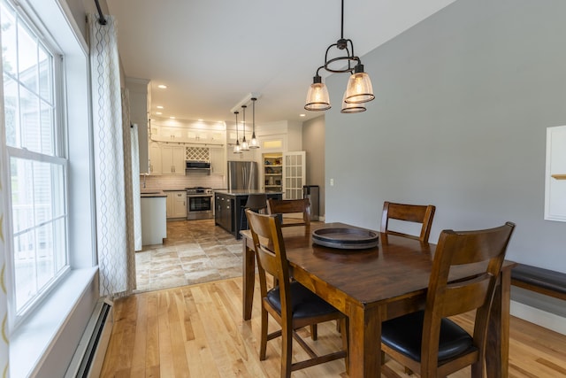 dining area featuring a notable chandelier, plenty of natural light, light wood-type flooring, and a baseboard radiator